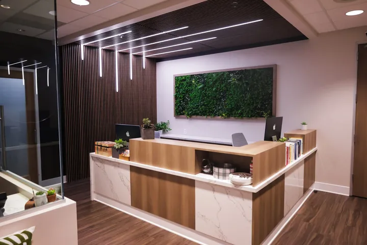 The reception desk at Thousand Oaks Family Dentistry, with a wood slat wall and a living plant wall behind it