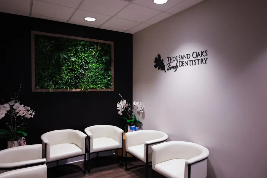 The waiting room at Thousand Oaks Family Dentistry, with the practice name on the wall beside a living plant wall